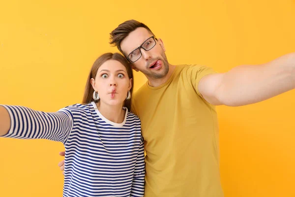 Pareja joven tomando selfie sobre fondo de color — Foto de Stock