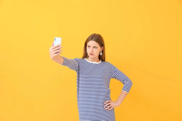 Schöne junge Frau macht Selfie auf farbigem Hintergrund — Stockfoto