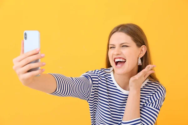 Schöne junge Frau macht Selfie auf farbigem Hintergrund — Stockfoto