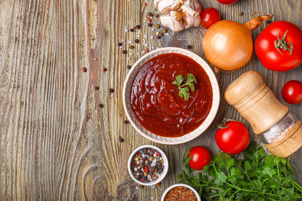 Bowl with tasty sauce and ingredients on wooden background