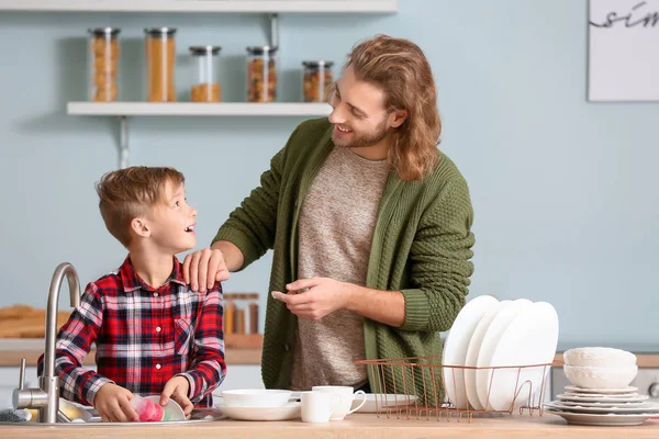 Father and son washing dishes in kitchen — Stock Photo, Image