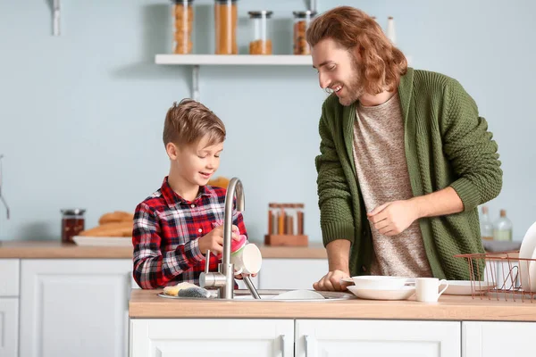 Father and son washing dishes in kitchen — Stock Photo, Image