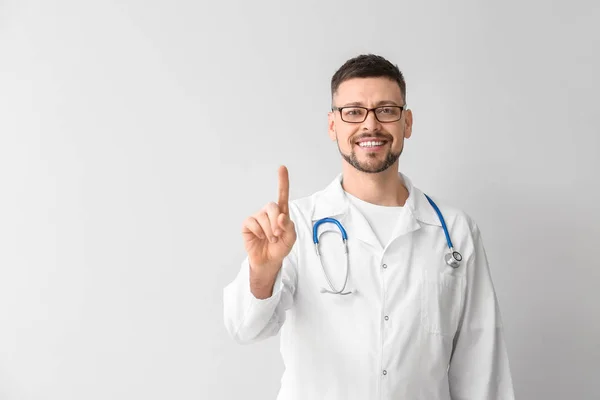 Cardiólogo masculino con dedo índice elevado sobre fondo claro —  Fotos de Stock