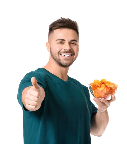 Hezký mladý muž s chutnými bramborové lupínky ukazující palec nahoru na bílém pozadí — Stock fotografie