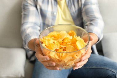 Evde lezzetli patates cipsleri olan yakışıklı genç adam, yakın plan.