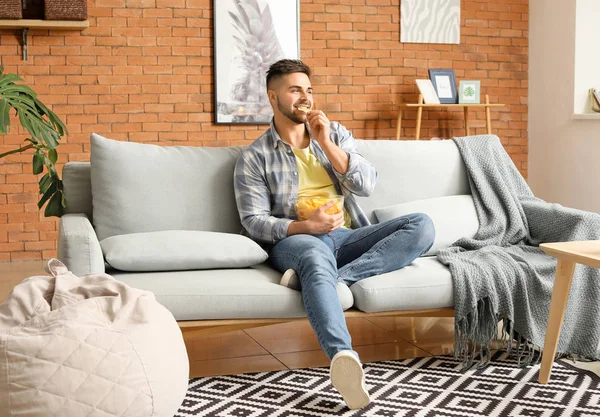 Evde patates cipsi yiyen yakışıklı genç adam.