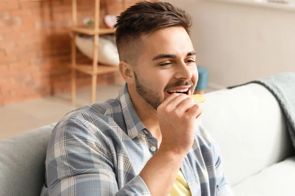 Guapo joven comiendo sabrosas papas fritas en casa —  Fotos de Stock