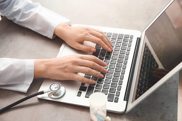 Médica feminina trabalhando em laptop à mesa — Fotografia de Stock