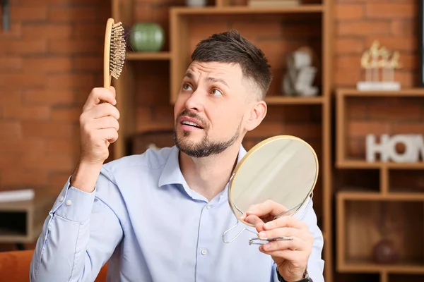Беспокойный мужчина с проблемой выпадения волос дома — стоковое фото