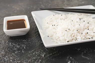 Kaynamış pirinç ve koyu arkaplanda soya soslu tabak.