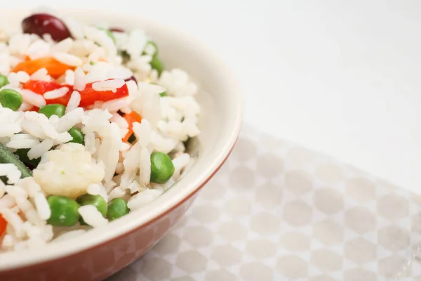 Tigela com arroz fervido e legumes no fundo branco, close-up — Fotografia de Stock