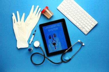 Ekranda urojenital sistemin resmi olan tablet bilgisayar, eldivenler, idrar örneği, şırınga ve renk arkaplanındaki bilgisayar klavyesi