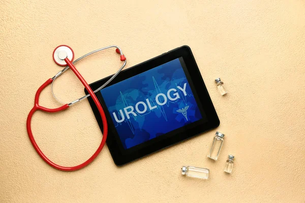 Tablet computador com palavra UROLOGIA na tela, estetoscópio e medicamentos em fundo de cor — Fotografia de Stock