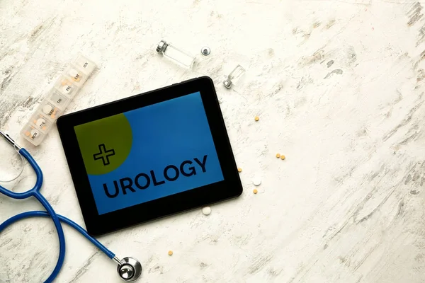 Компьютер со словом UROLOGY на экране, стетоскоп и лекарства на белом фоне — стоковое фото