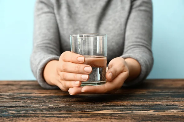Žena trpící Parkinsonovým syndromem se sklenicí vody sedící u stolu, detailní záběr — Stock fotografie