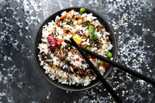 Boiled rice with vegetables in bowl on dark background