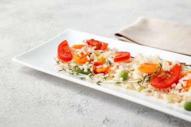 Hafif arka planda haşlanmış pirinç ve sebzeli tabak, yakın plan.