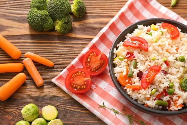 Boiled rice with vegetables in frying pan on wooden table — Stock Photo, Image