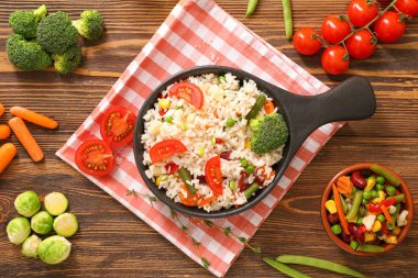 Ahşap masada tavada sebzeli haşlanmış pirinç.