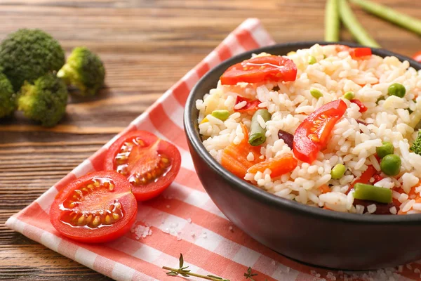 Boiled rice with vegetables in frying pan on wooden table, closeup — Stock Photo, Image