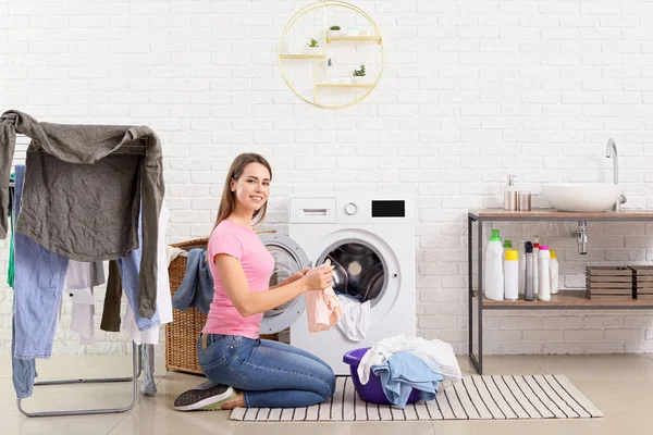 Молодая домохозяйка стирает белье дома — стоковое фото