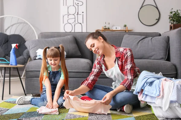 Jovem dona de casa e sua filha pequena com lavanderia em casa — Fotografia de Stock