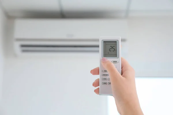 Jeune femme allumant le climatiseur à la maison, gros plan — Photo