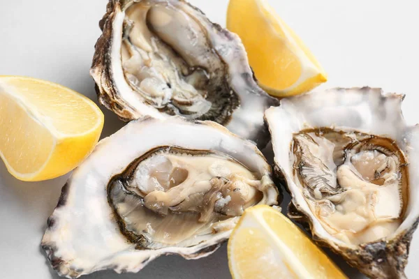 Tasty oysters with lemon on white background, closeup — Stock Photo, Image