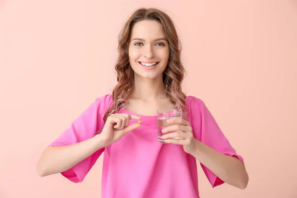 Young woman with fish oil on color background — Stock Photo, Image