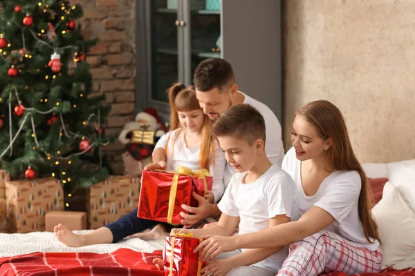 Família feliz com presentes de Natal sentados na cama em casa — Fotografia de Stock
