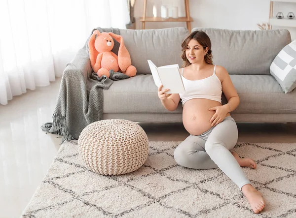 Красивая беременная женщина читает книгу дома — стоковое фото