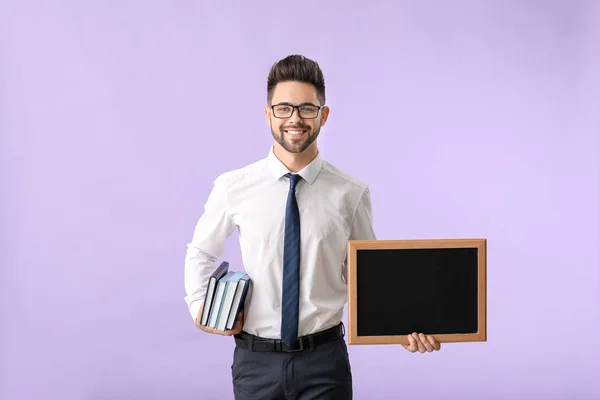 Männlicher Lehrer mit Kreidetafel auf farbigem Hintergrund — Stockfoto