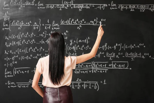 Vrouwelijke leraar schrijven op blackboard in klas — Stockfoto