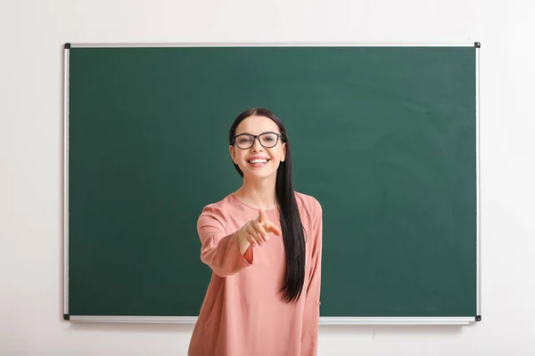 Vrouwelijke leraar in de buurt van schoolbord in de klas — Stockfoto