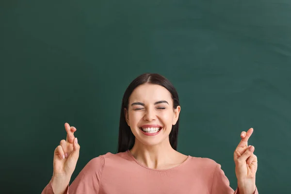 Vrouwelijke student met gekruiste vingers in de buurt van schoolbord in de klas — Stockfoto