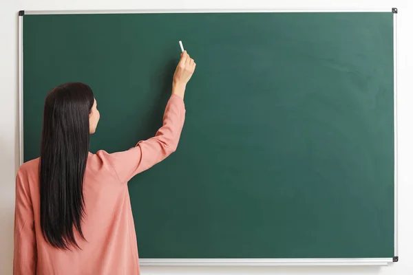 Lehrerin schreibt auf Tafel im Klassenzimmer — Stockfoto