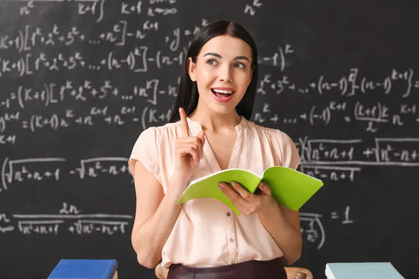 Vrouwelijke leraar in de buurt van schoolbord in de klas — Stockfoto