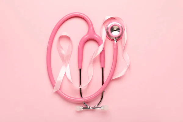 Fita rosa com estetoscópio sobre fundo de cor. Conceito de consciência do câncer de mama — Fotografia de Stock