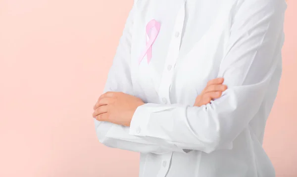 Giovane donna con nastro rosa su sfondo di colore, primo piano. Concetto di sensibilizzazione sul cancro — Foto Stock