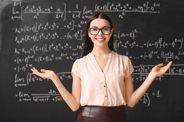 Vrouwelijke leraar in de buurt van schoolbord in de klas — Stockfoto