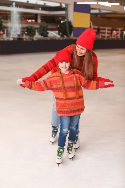 Joven madre con hija pequeña en pista de patinaje — Foto de Stock