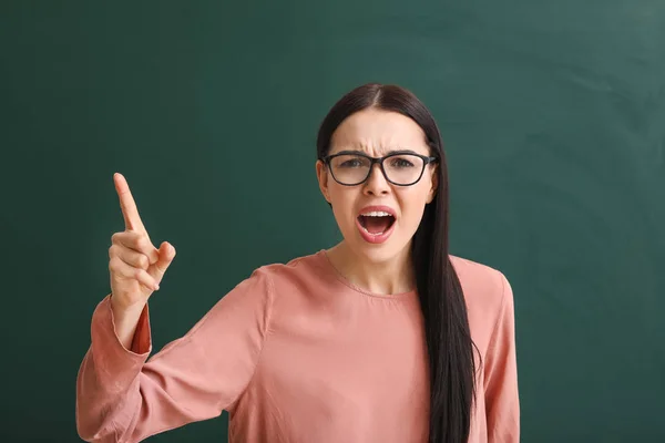 Angry female teacher near blackboard in classroom — Stock Photo, Image