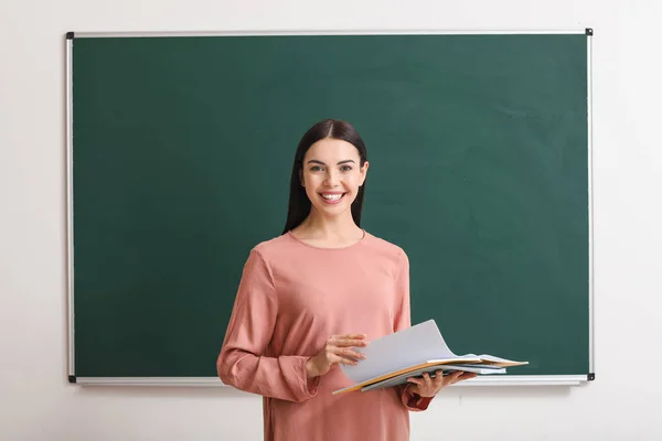 Professora perto de quadro negro em sala de aula — Fotografia de Stock