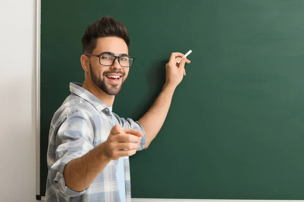 Male teacher writing on blackboard in classroom — Stock Photo, Image