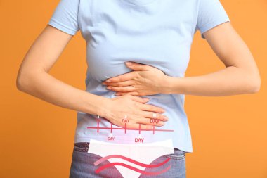 Arka planda adet sancısı çeken genç bir kadın.