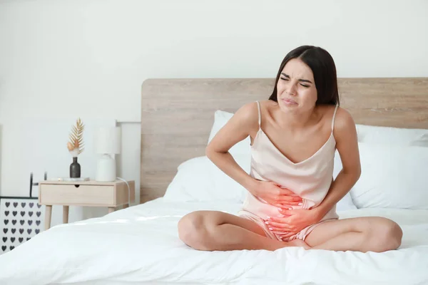 Young woman suffering from menstrual cramps in bedroom — Stock Photo, Image