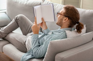 Evde kitap okuyan yakışıklı genç adam.