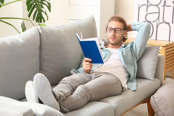 Joven guapo leyendo libro en casa — Foto de Stock