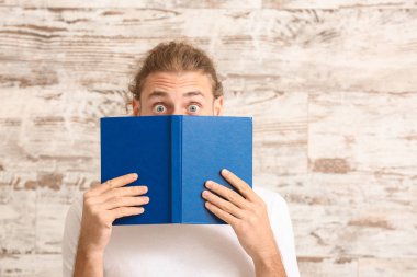 Ahşap duvarın yanında kitabı olan genç adam şaşırdı.