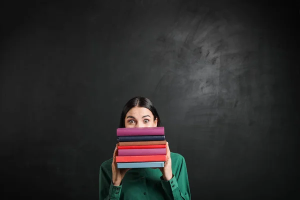 Female teacher with books near blackboard in classroom — Stock Photo, Image